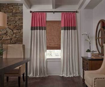 Drapes/Valances A window with pink, brown, and white curtains, bamboo shade, and surrounding modern furniture in a dining room.