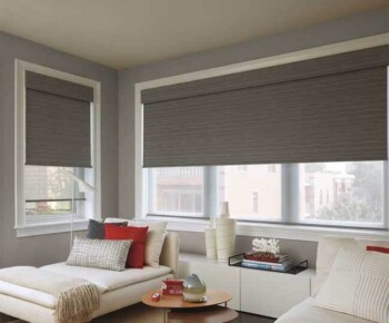 Rollers/Roman A modern living room with gray walls, large windows with roller shades, white furniture, and decorative pillows.
