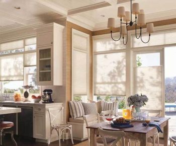 Shades Bright kitchen and dining area with large windows, a wooden table, bench seating, and flowers on the table.